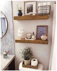 a bathroom with two wooden shelves above the toilet and a mirror on the wall behind it