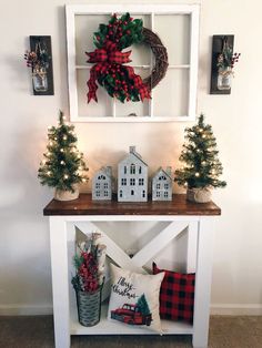 a white table with christmas decorations on it and a wreath hanging above the top shelf