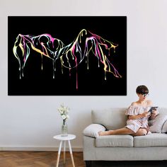 a woman sitting on top of a couch in front of a black wall with pink and yellow paint