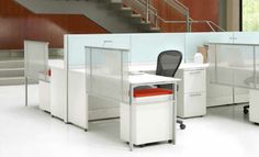 an office cubicle with two desks and one chair in front of the stairs