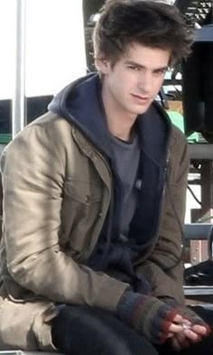 a young man sitting on top of a metal bench