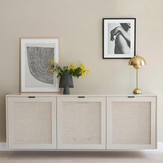 a white sideboard with two pictures on the wall