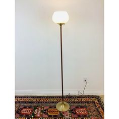 a floor lamp with a white light on top of it next to a colorful rug