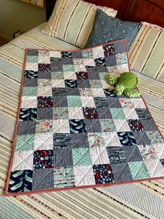 a quilted bed with a green stuffed animal on top of it and pillows in the background