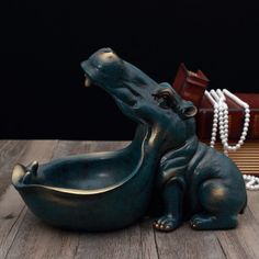 a statue of a hippopotamus sitting on a table next to a book