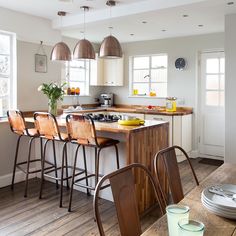 a kitchen filled with lots of counter top space and wooden chairs next to an island