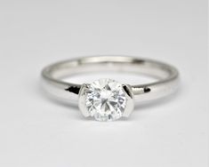 a white gold engagement ring with a round brilliant cut diamond in the center, on a plain surface