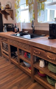 a kitchen with wooden cabinets and counter tops next to a window filled with yellow curtains