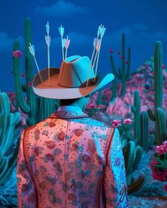 a man wearing a cowboy hat with arrows sticking out of it's back, standing in front of cacti