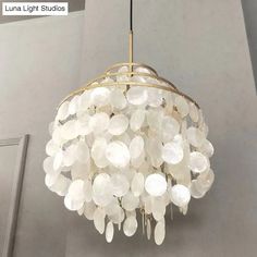 a chandelier hanging from the ceiling with lots of white glass discs on it