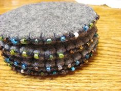 three small gray coasters sitting on top of a wooden table