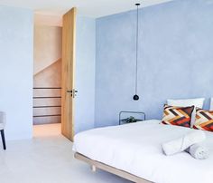 a bedroom with blue walls and white bedding