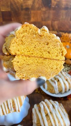 a person holding up a piece of pumpkin spiced biscuit in front of other pastries