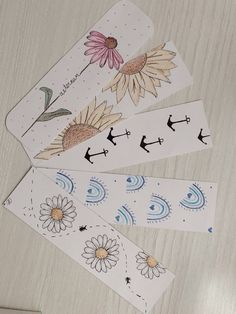 four stickers with flowers on them sitting on top of a wooden table next to scissors