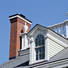 the top of a building with a clock on it's face and a brick chimney