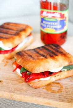 two grilled sandwiches sitting on top of a cutting board next to a jar of ketchup