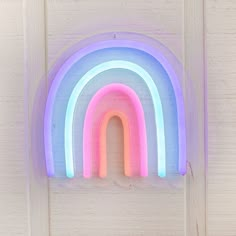 a rainbow shaped neon sign mounted to the side of a wall