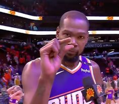 a basketball player making the peace sign with his hand while standing in front of an audience