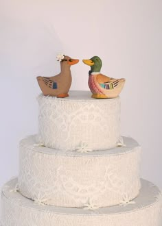 two wooden ducks sitting on top of a wedding cake