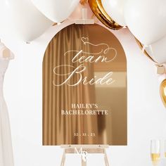 a sign that says team bride on it next to some white balloons and gold foil