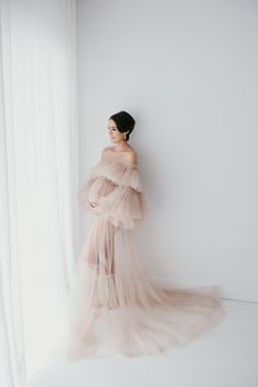 a woman standing in front of a white wall wearing a dress with ruffles