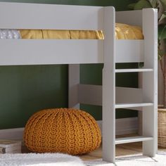 a white bunk bed sitting in a bedroom next to a yellow ottoman and green walls