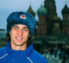 a man wearing a blue jacket and hat in front of a building with domes on it