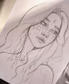 a drawing of a woman's face with teary eyes and long hair is on top of a piece of paper