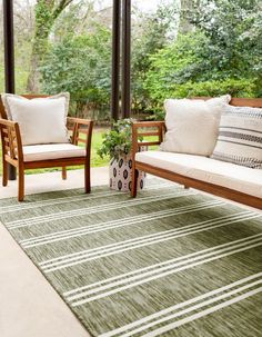 two wooden chairs sitting on top of a black and white rug next to a couch