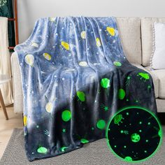 a blanket with green planets and stars on it next to a couch in a living room