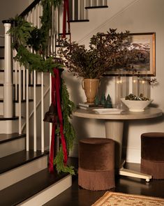 a table with two chairs and a plant on it in front of a stair case