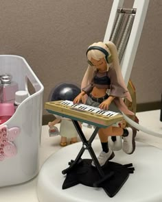 a small figurine sitting on top of a musical keyboard next to a white container