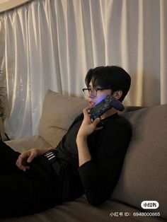 a man sitting on a couch holding a remote control