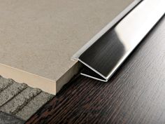 a close up view of a wooden floor with a metal strip on the side and an area rug underneath it