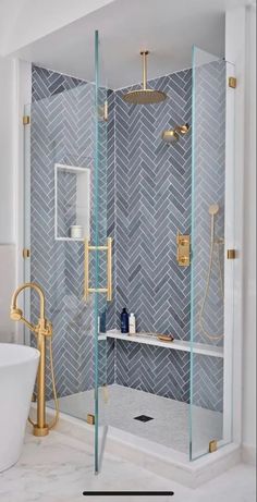 a white bath tub sitting next to a walk in shower with a glass door and gold fixtures