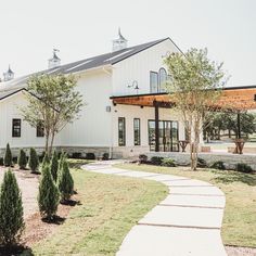 a large white barn with a walkway leading to the front door and side entrance area