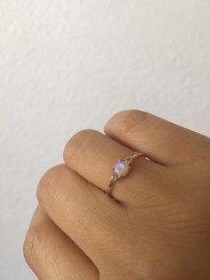 a woman's hand with a ring that has a white opal in it