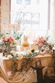 a table topped with a cake and flowers next to a window filled with lots of windows