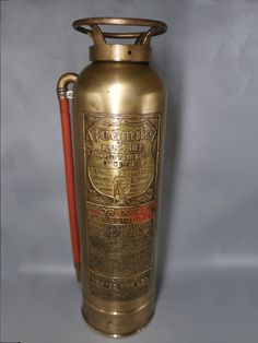 an old fashioned brass fire extinguisher with a red handled stick in it's mouth