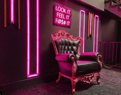 a chair sitting in front of a purple wall with neon lights on it's sides