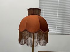 a lamp that is sitting on top of a wooden table next to a window with blinds