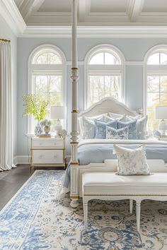 a bedroom with blue walls and white furniture in the corner, along with large windows