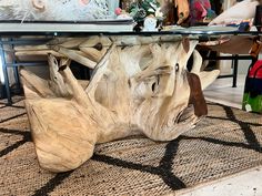 a table made out of driftwood with glass top and metal base, sitting on a rug