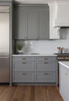 a kitchen with gray cabinets and white counter tops, wood flooring and stainless steel appliances