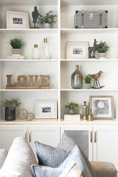 a living room filled with lots of white bookshelves covered in pictures and plants