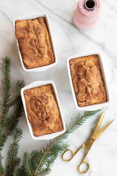 three small white dishes filled with baked goods next to scissors and sprigs of pine