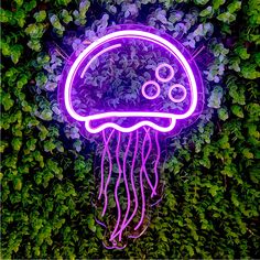 a neon purple jellyfish floating on top of green plants