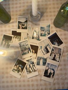 many polaroid photos are laying on the table next to a candle and some vases