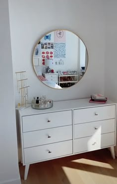 a white dresser with a round mirror above it