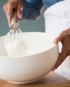 a person whisking whipped cream in a white bowl